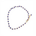 anklet with puprple beads and gold chain on a white background