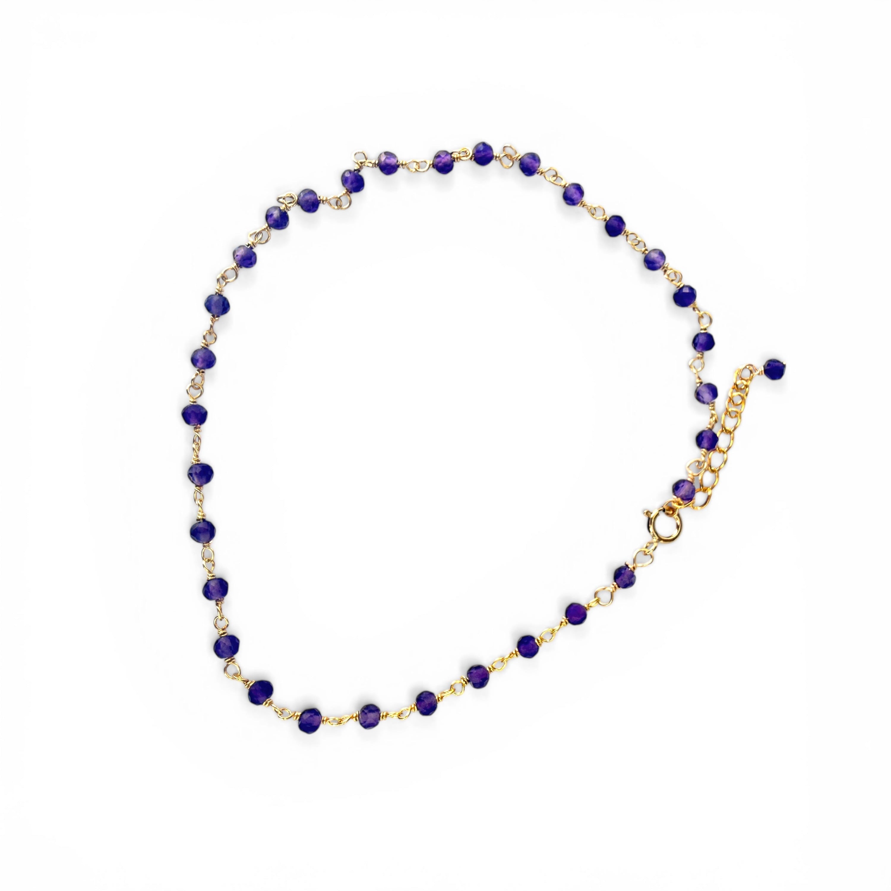anklet with puprple beads and gold chain on a white background